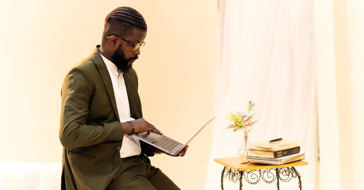 Un homme bien habillé dans un bureau de Lagos concentré sur son ordinateur portable, adoptant un espace de travail numérique moderne.