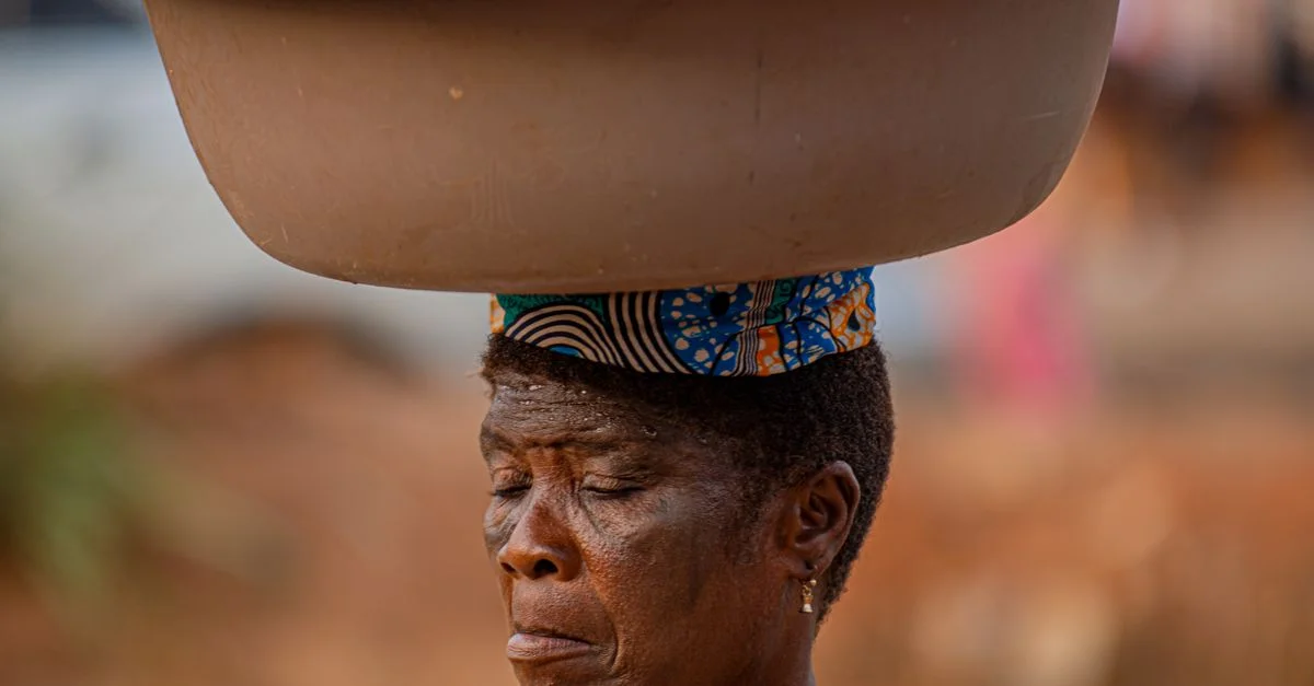 Une femme africaine au Nigeria équilibre un bassin de sachets d'eau sur sa tête, mettant en avant le commerce de rue local.