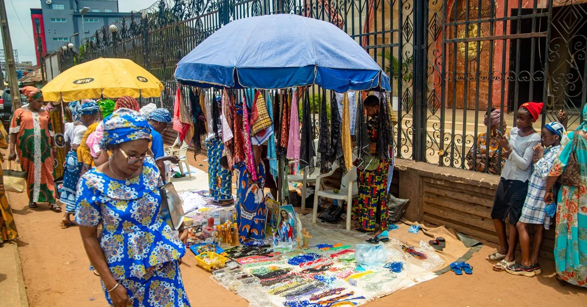 Scène de marché coloré en plein air à Benin City, Nigeria, présentant des tissus vibrants et des marchandises locales.