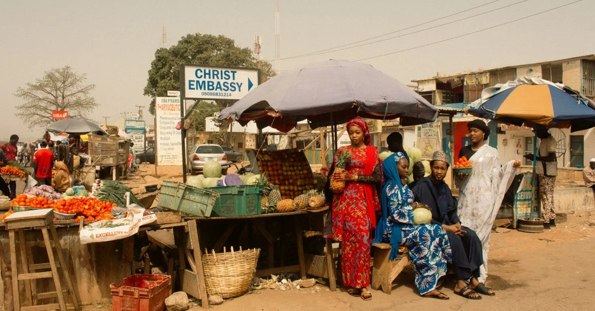 Des vendeurs locaux présentent des fruits tropicaux dans une rue de marché animée en Afrique, riche en culture et en couleur.
