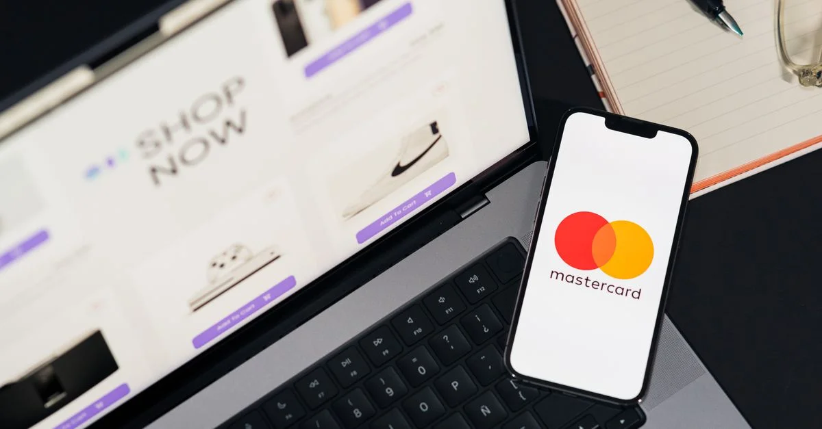 Ordinateur portable et smartphone avec le logo Mastercard, illustrant les achats en ligne et les paiements numériques.