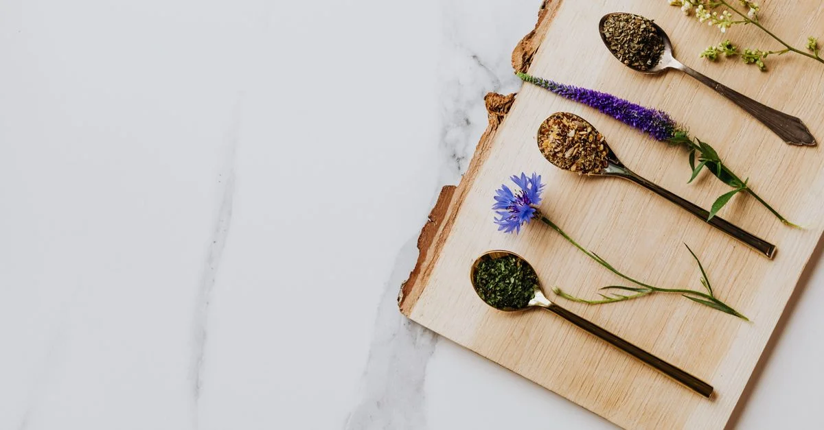 Un joli agencement de tisanes et de fleurs sur une planche en bois. Parfait pour des thèmes culinaires ou de bien-être.